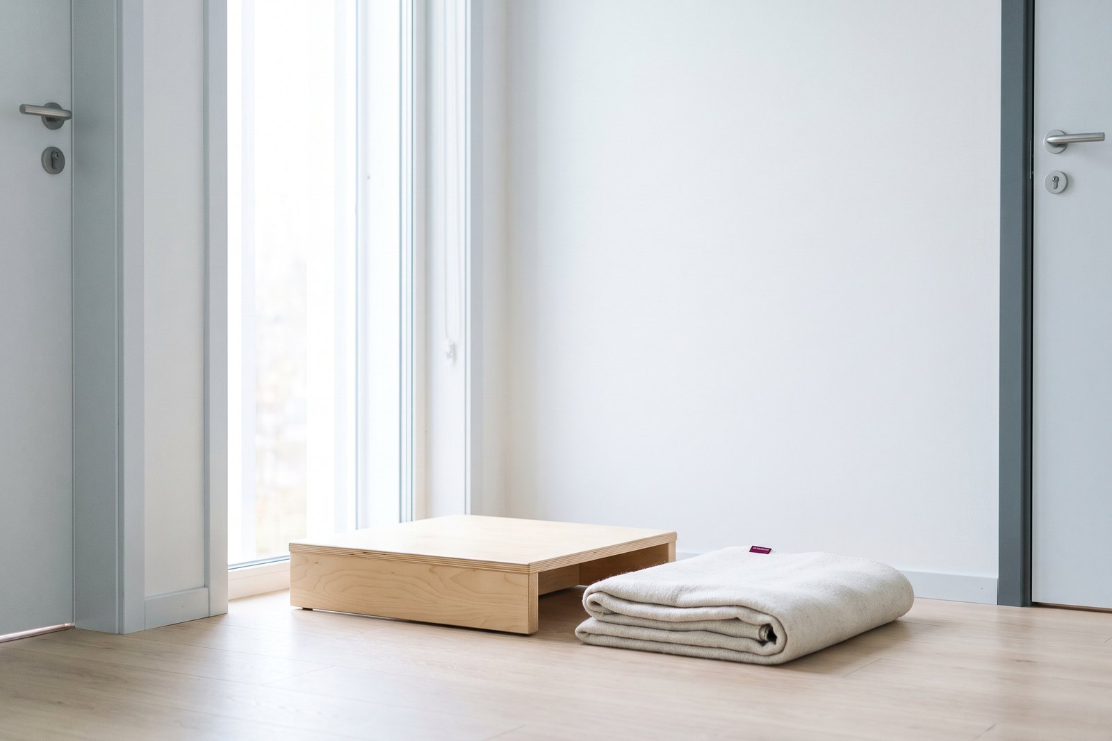 A balance platform and a folded blanket on pale wood by a window