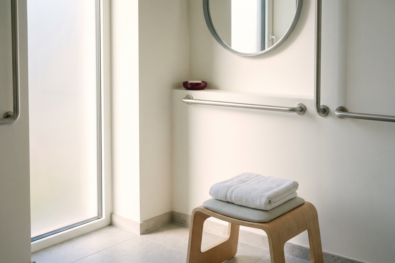 Grab rails and a folded towel in a bright, simple clinic bathroom