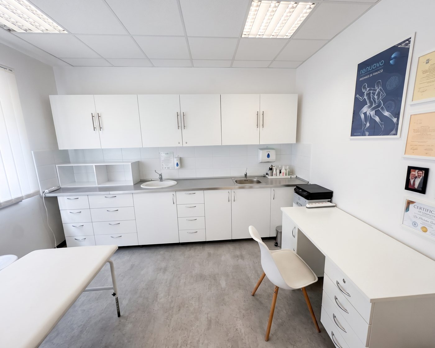 A treatment room with a preparation counter, wash basin and framed certificates